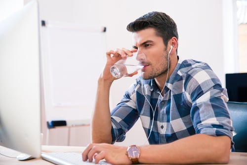 Handsome businessman in casual cloth using PC and drinking water in office