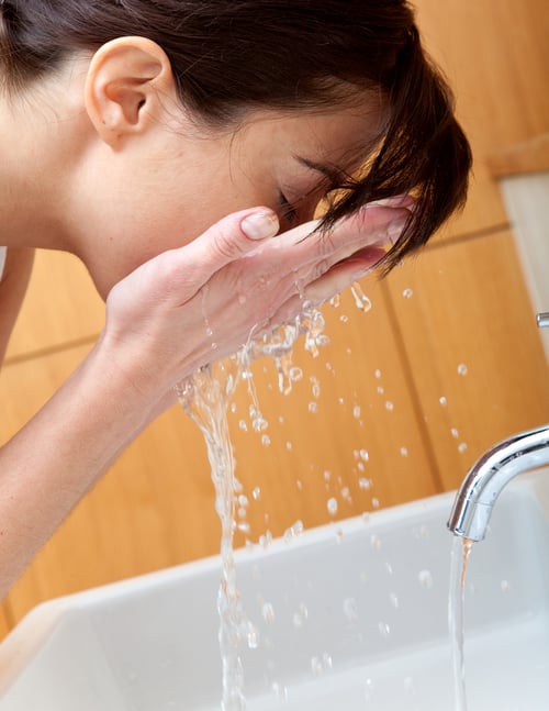 Woman at the bathroom washing her face