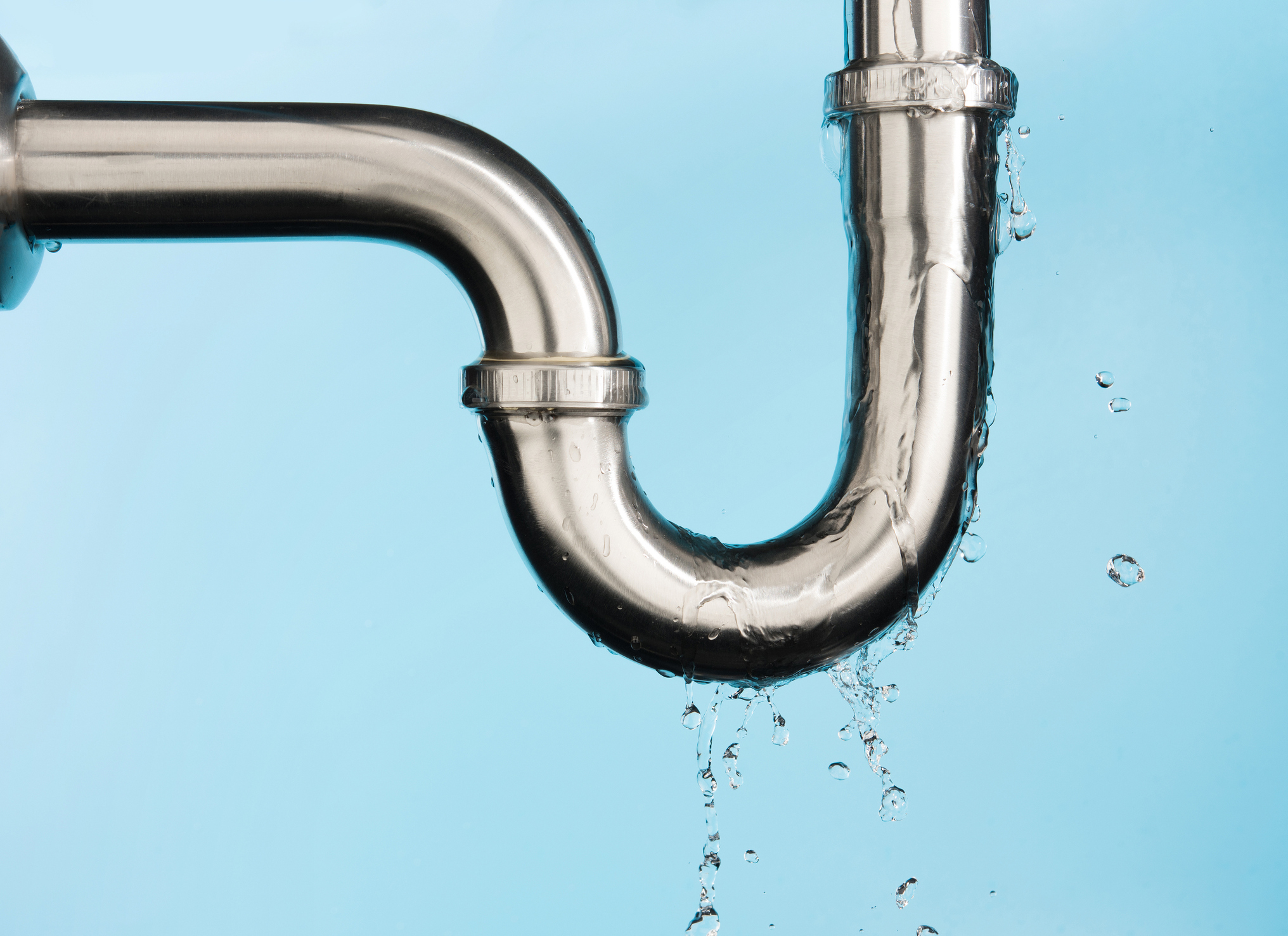 Leaking water from a sink pipe on light blue background