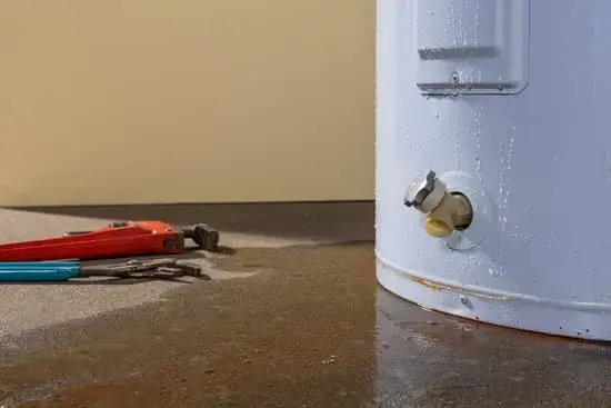 Leaking water heater with plumbing tools next to it